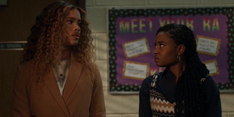 Standing side by side, two competitors for the SGA presidency, turn their heads to face the other. Nathaniel is on the left wearing a dark khaki tie waist blazer with a pearl white satin shirt underneath. Wilinda is on the right, wearing a navy button-up beneath a cashmere tank.