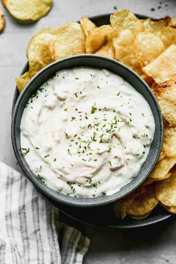 A bowl of clam dip next to potato chips