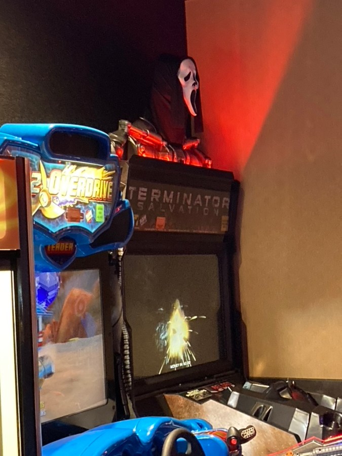 a ghostface mask on top of a terminator video arcade machine 