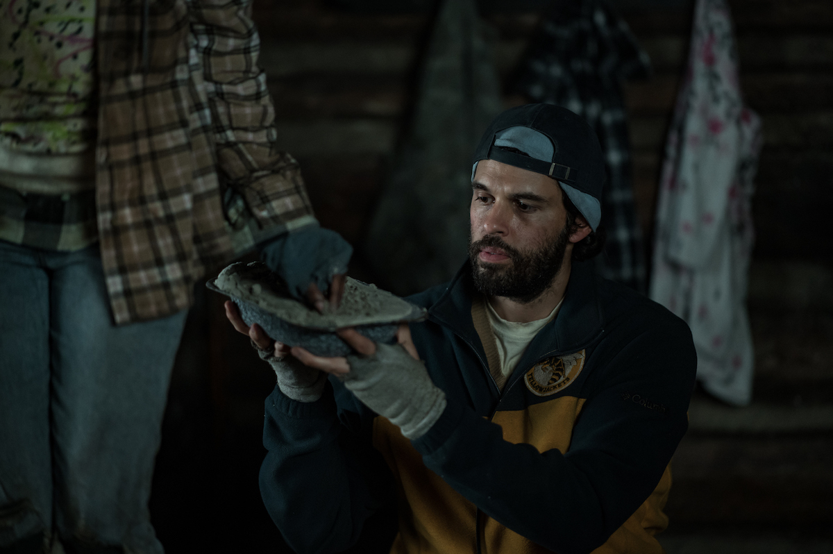 Steven Krueger as Ben Scott in YELLOWJACKETS Season 2 holds up a boot. Photo Credit: Kailey Schwerman/SHOWTIME.