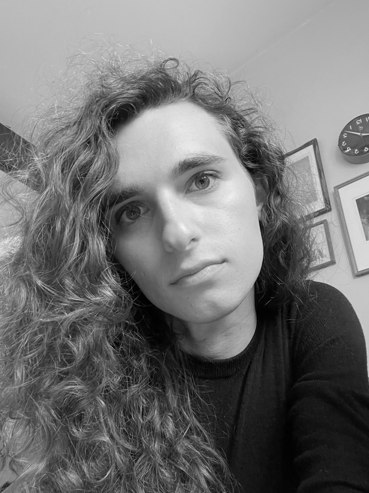 a black and white photo of drew, a white woman, with long curly hair, leaning toward the camera, looking moody