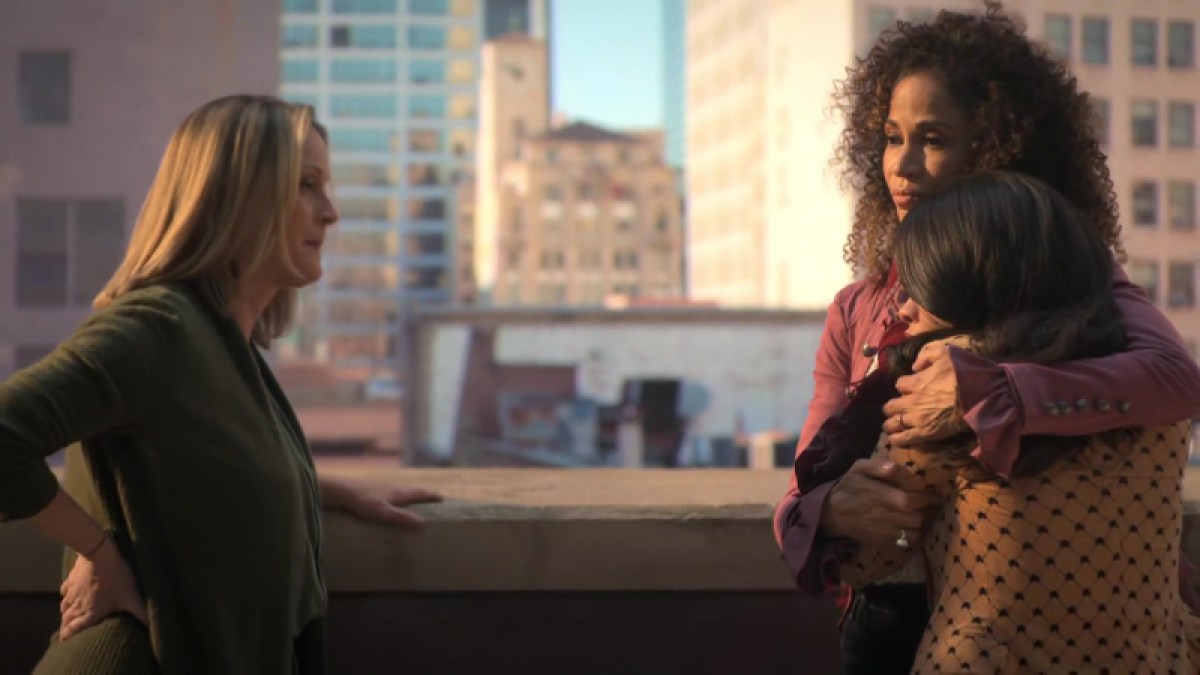 Lena (on the right) wraps Mariana in an embrace as Stef looks on. They're all on the Coterie rooftop. 