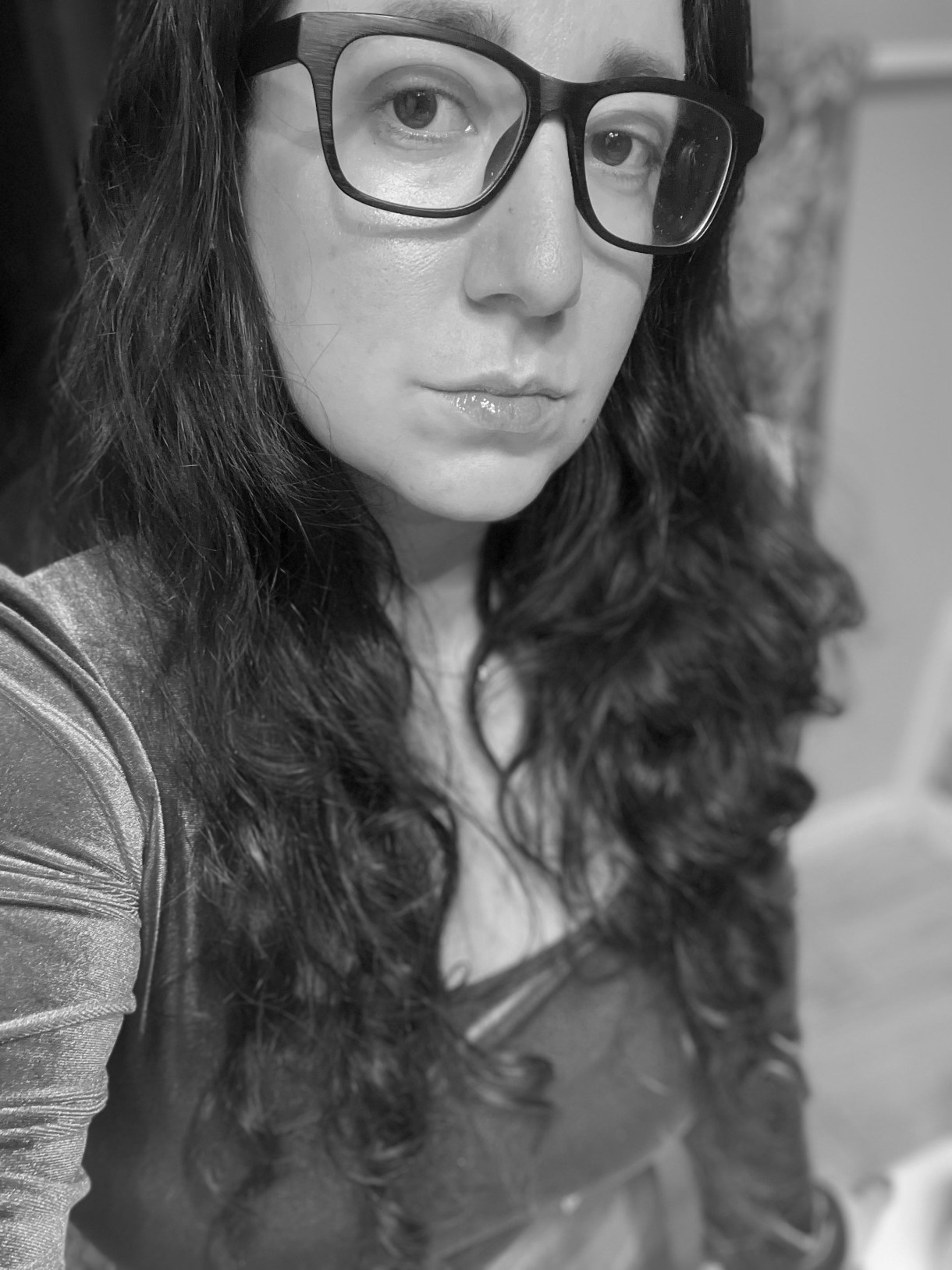 a black and white photo of Vanessa, a white woman, with long brown hair and thick glasses, looking serious