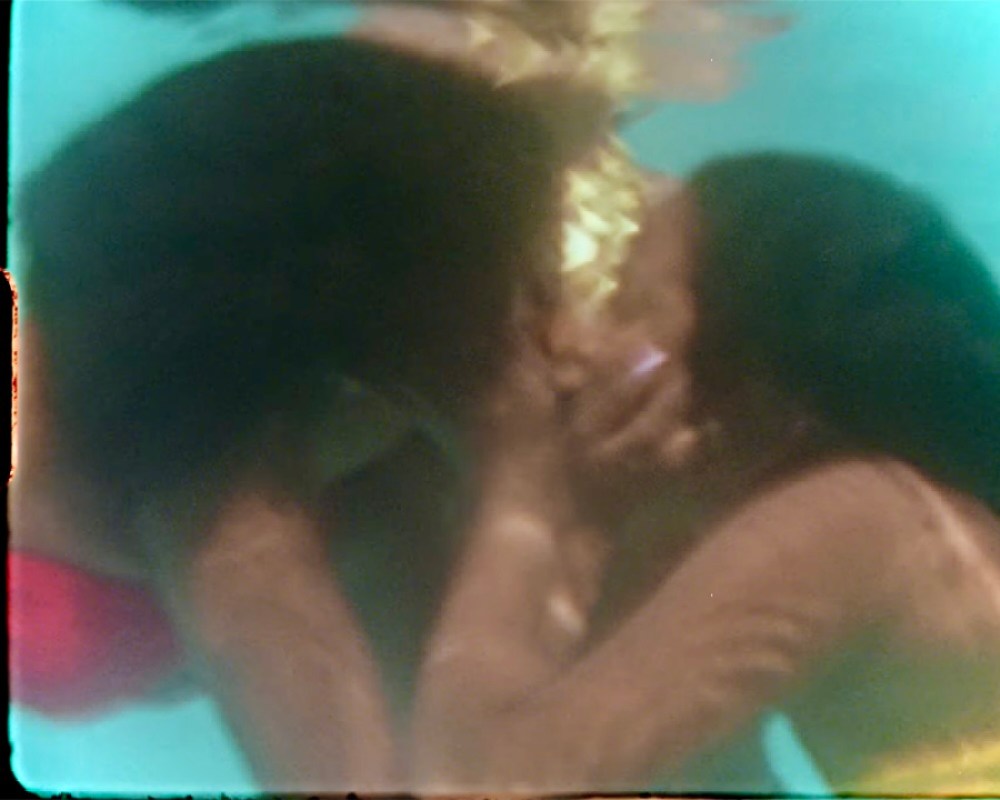 In a still from Janelle Monae's Lipstick Lover music video, two black women kiss underwater.