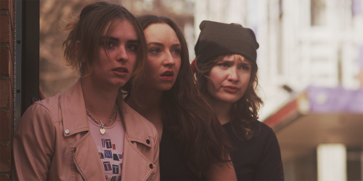 Three castmembers from T Blockers stand in a group looking concerned