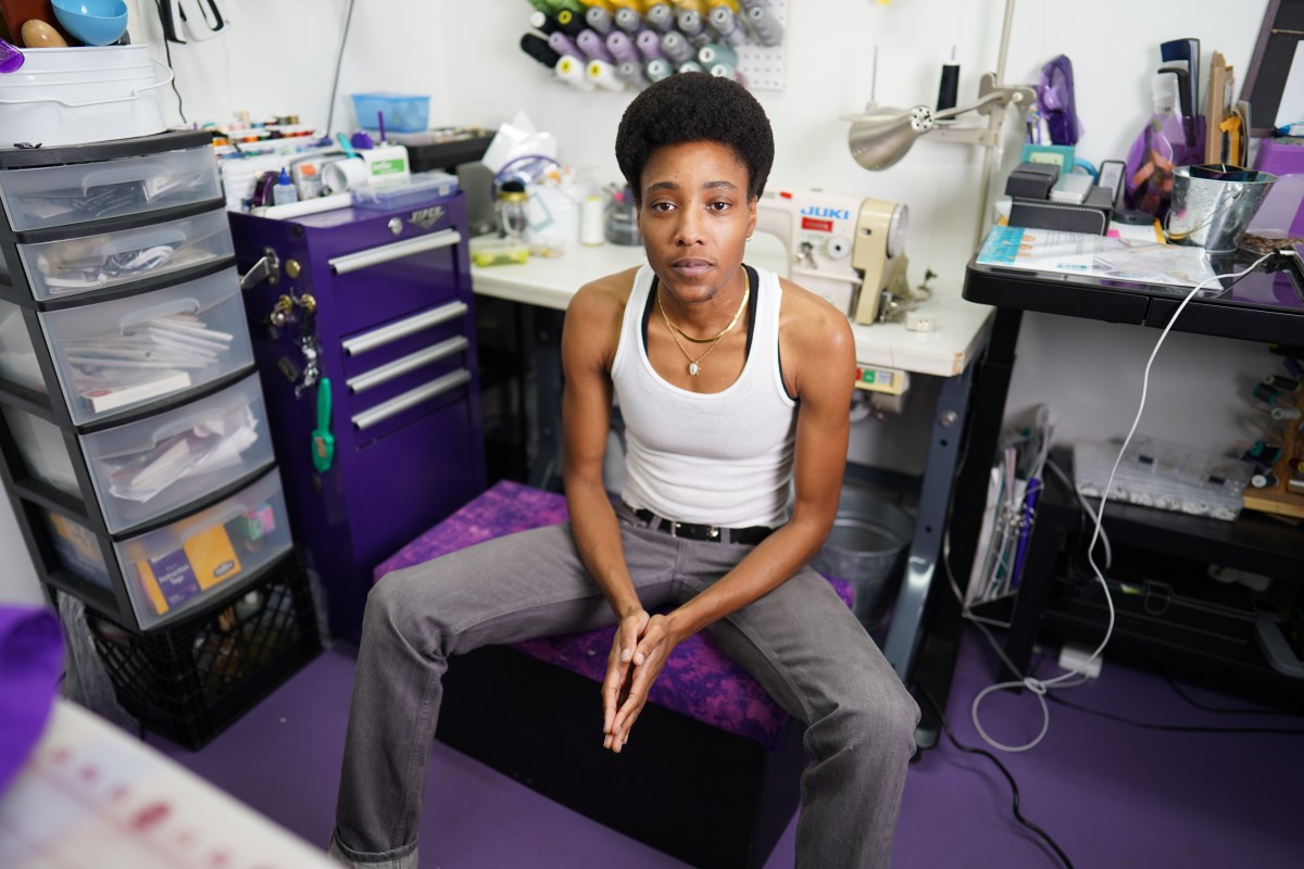 a Black stud sits in a chair wearing a white tank and gray jeans