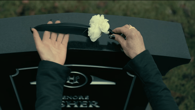 Verna places a raven feather and white flower on Lenore's tombstone