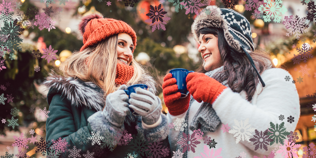 two women at a holiday market having cocoa