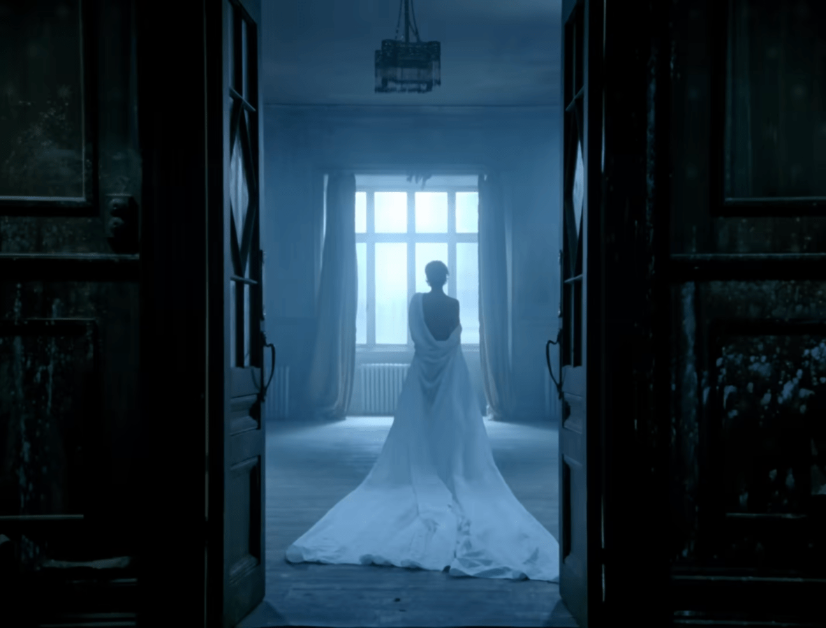 Freedom 90 queer: Christy Turlington walking toward a window with a white sheet wrapped around her