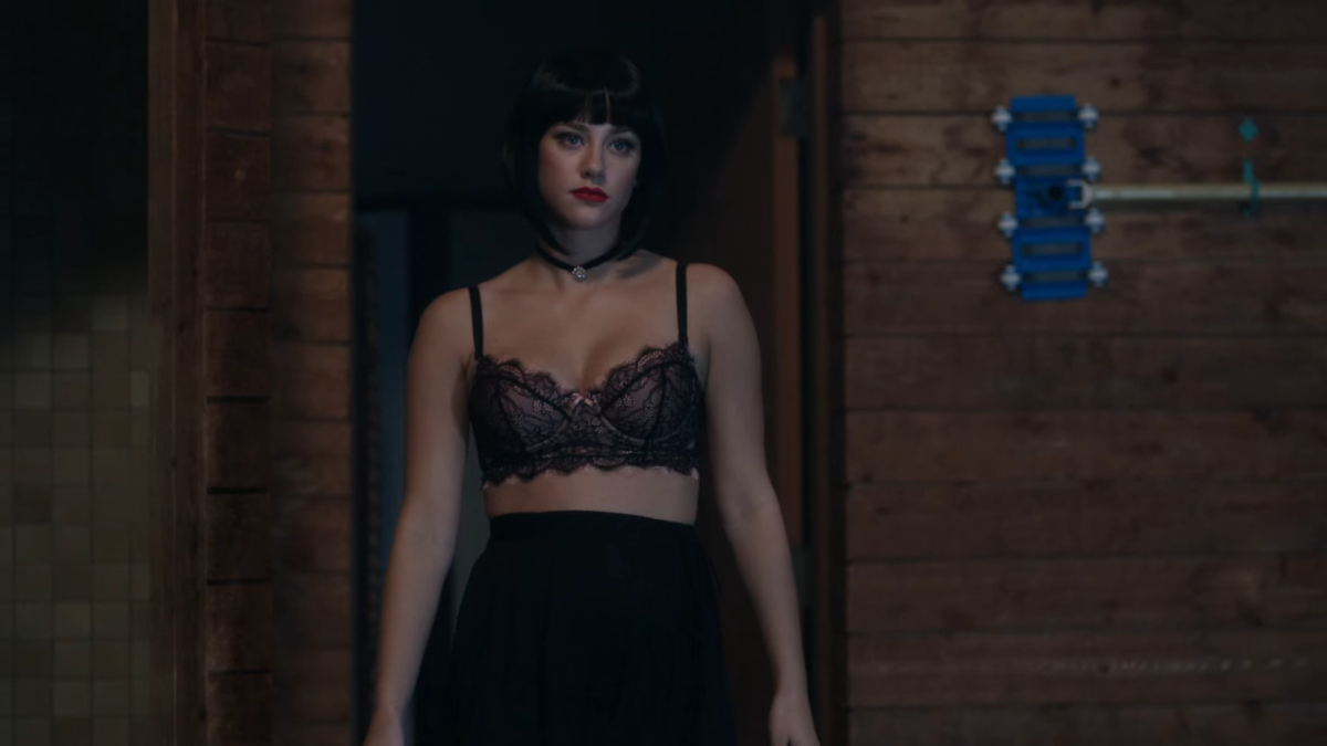 Betty in a black bob wig and a bra.