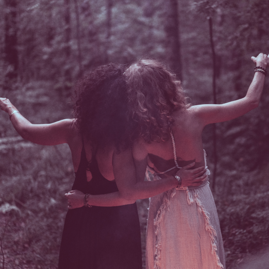 Two femmes embracing in the woods