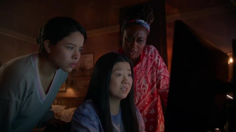 Mariana, Alice and Malika gather around a computer and review the footage from the security camera in the Coterie lobby.