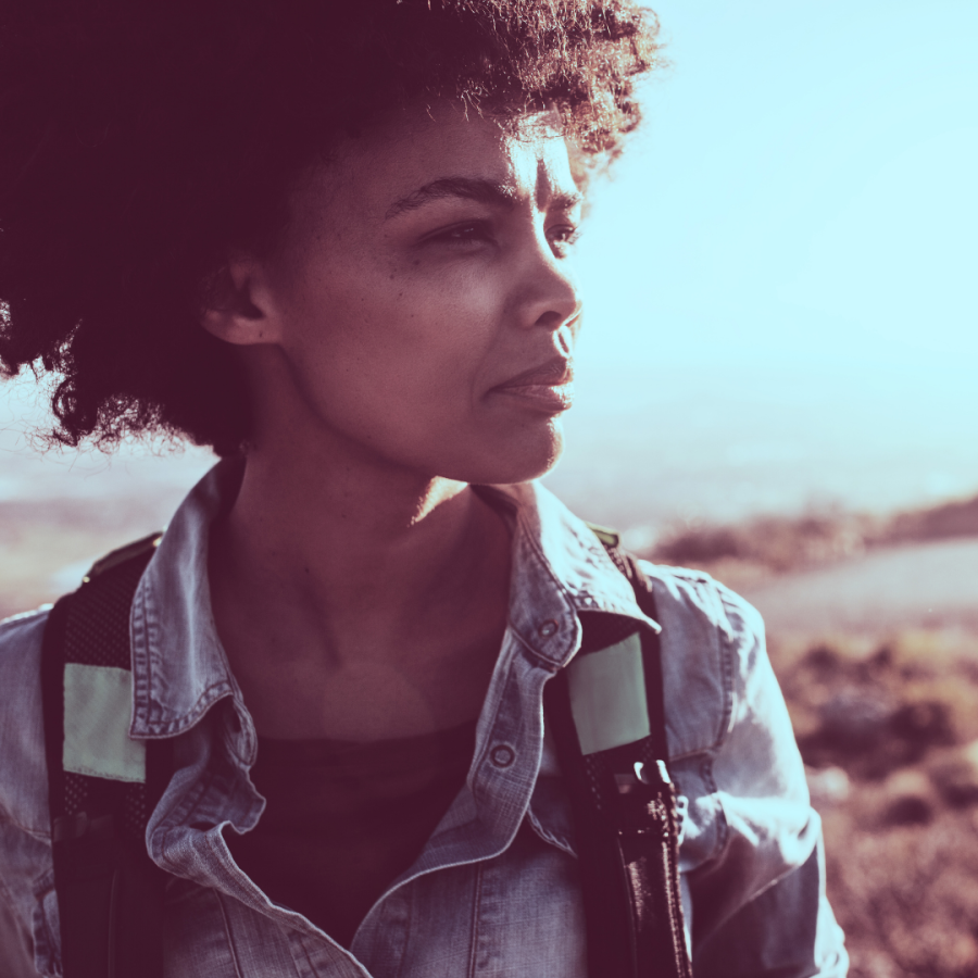 A black person with a large afro starring off into the sky against a desert background