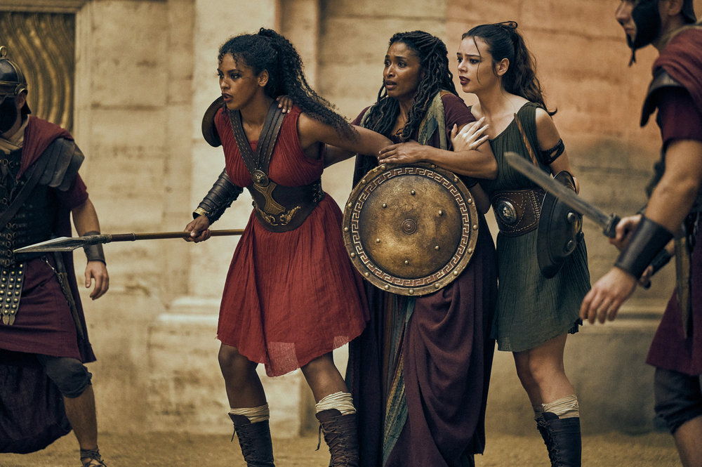 THOSE ABOUT TO DIE -- Episode 110 -- Pictured: (l-r) Kyshan Wilson as Aura, Sara Martins as Cala, Romana Maggiora Vergano as Selena -- (Photo by: Reiner Bajo/Peacock)