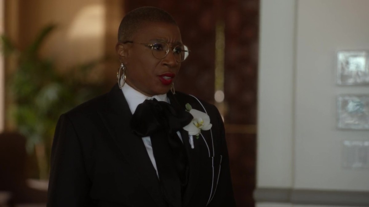 Hen in her "best person" suit for Chimney's wedding. Hen is wearing a black suit with white piping running down her left shoulder. She's wearing a black bow as a tie with flower affixed to her breast pocket.