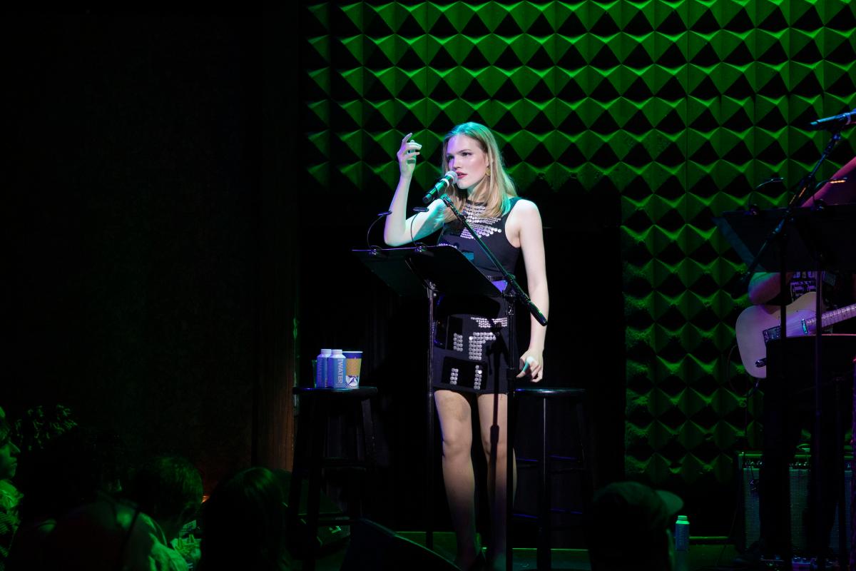 Doll/Girl musical: Murphy Taylor Smith performs on stage in a black dress with silver discs on it.