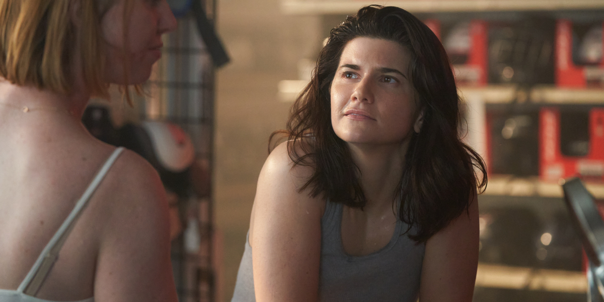 Elise Bauman in a tank top looks up at a woman.