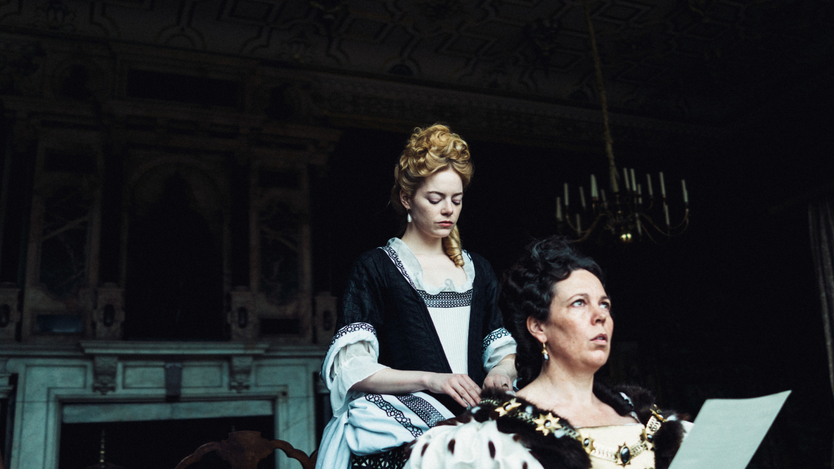 Emma Stone adjusts the collar of Olivia Colman.