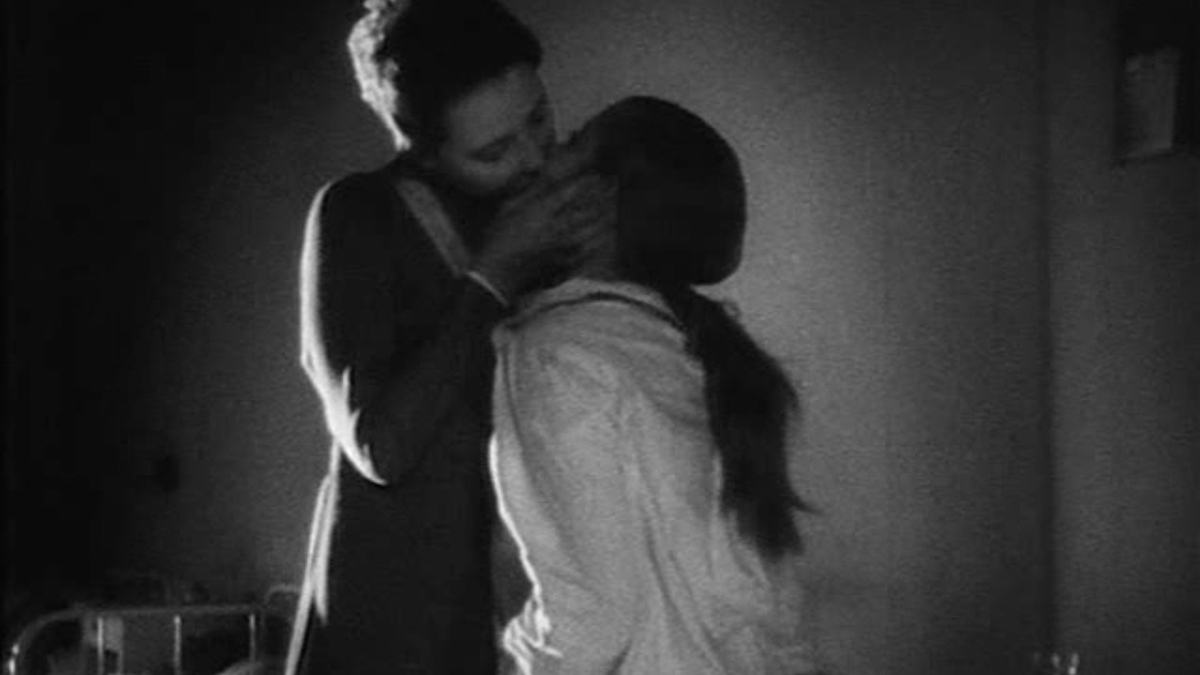 A black and white image of woman kissing a girl on the mouth.