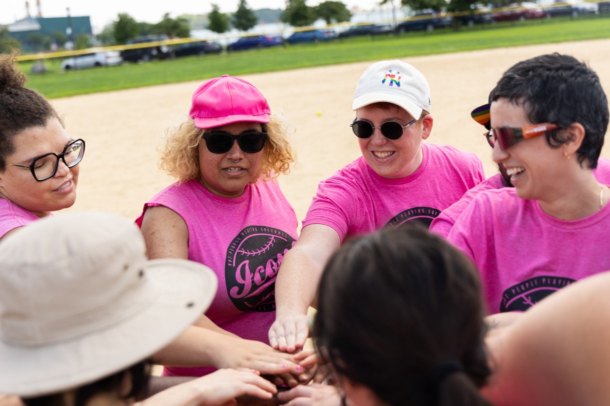 a team brings their hands in before a softball game