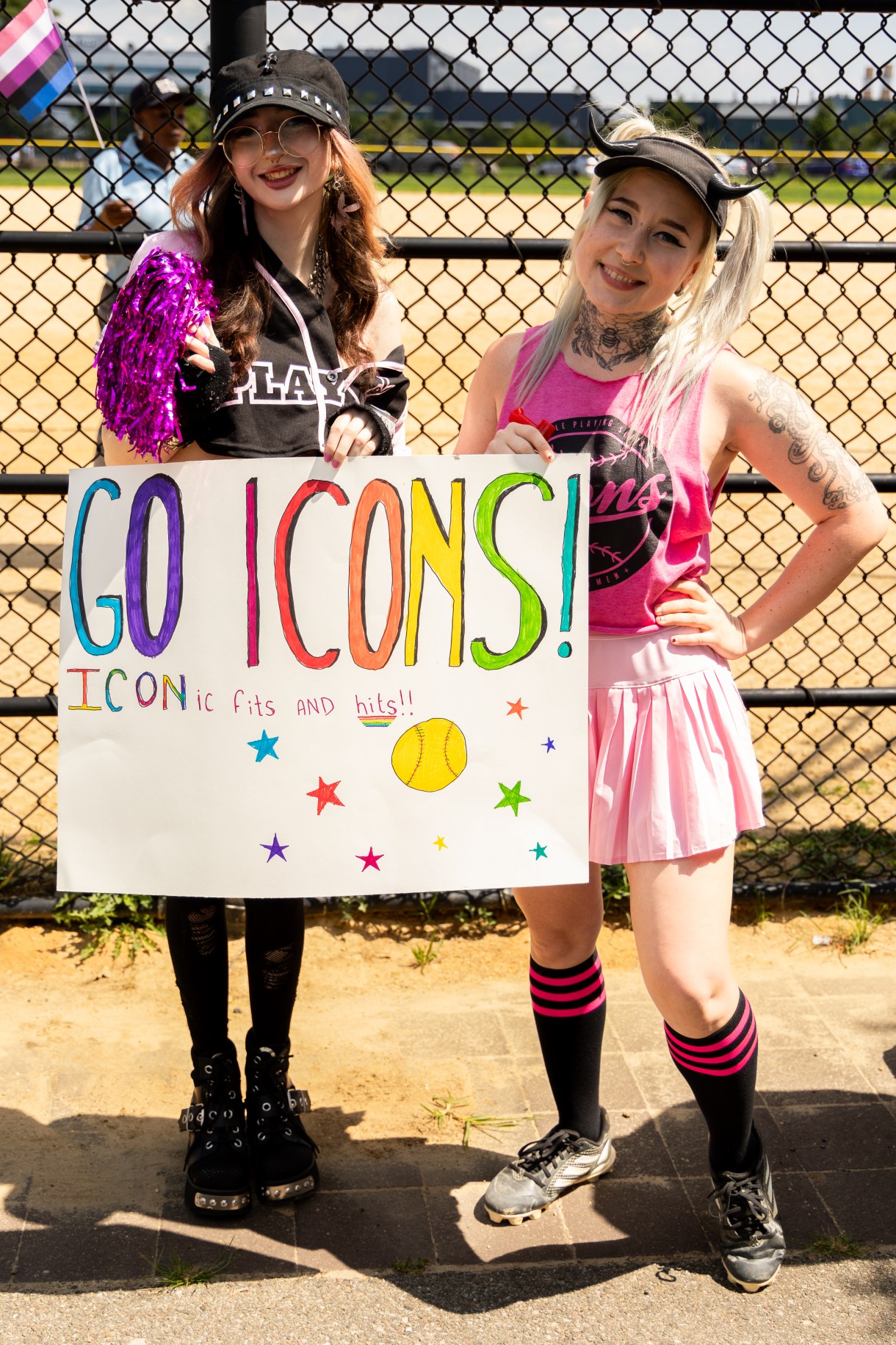 two softball fans hold a sign that says GO ICONS