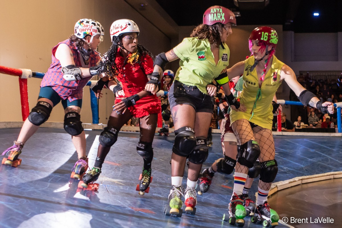 A group of skaters look serious as they bump into each other on the rink.