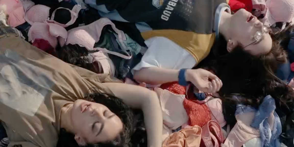 Charli XCX and Billie Eilish on a pile of bras in Guess