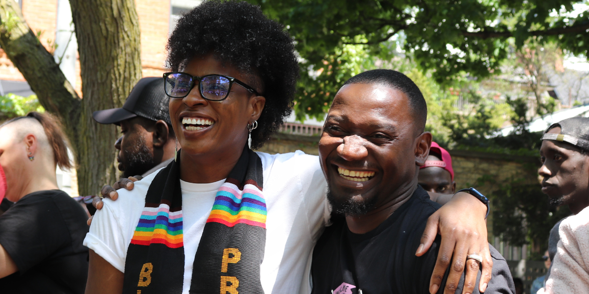 Latoya Nugent smiles with her arm around someone for Rainbow Railroad.