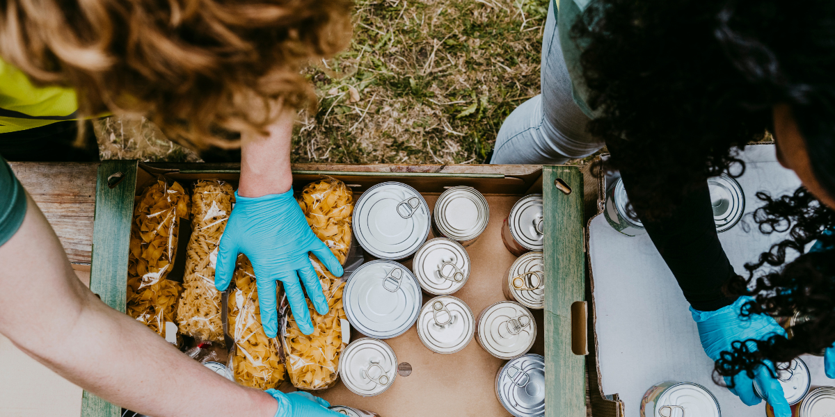 Two people organize cans and bags of food in cardboard contianers.