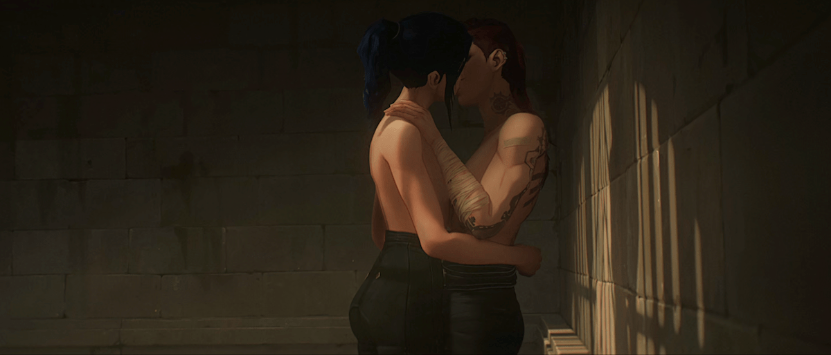 Cait and Vi kiss topless in the shadows.