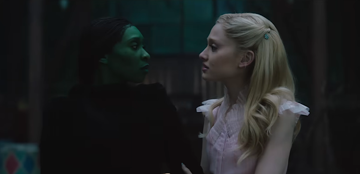 Elphaba and Glinda look at each other in a dark room.