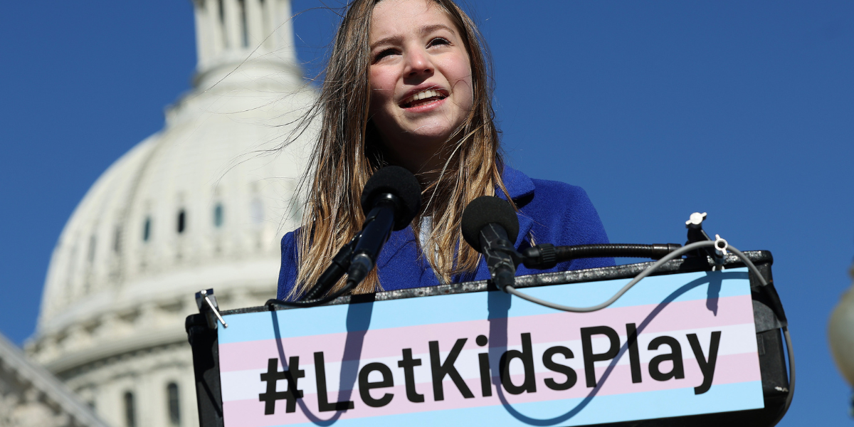 a young trans athlete speaks in front of Congress building against trans sports bans