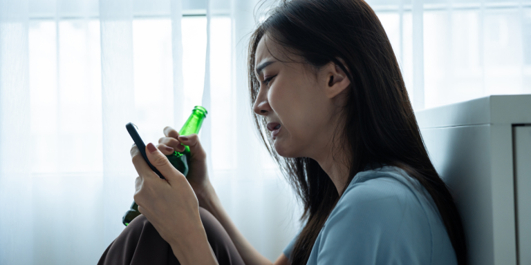 a woman crying on her phone with a beer