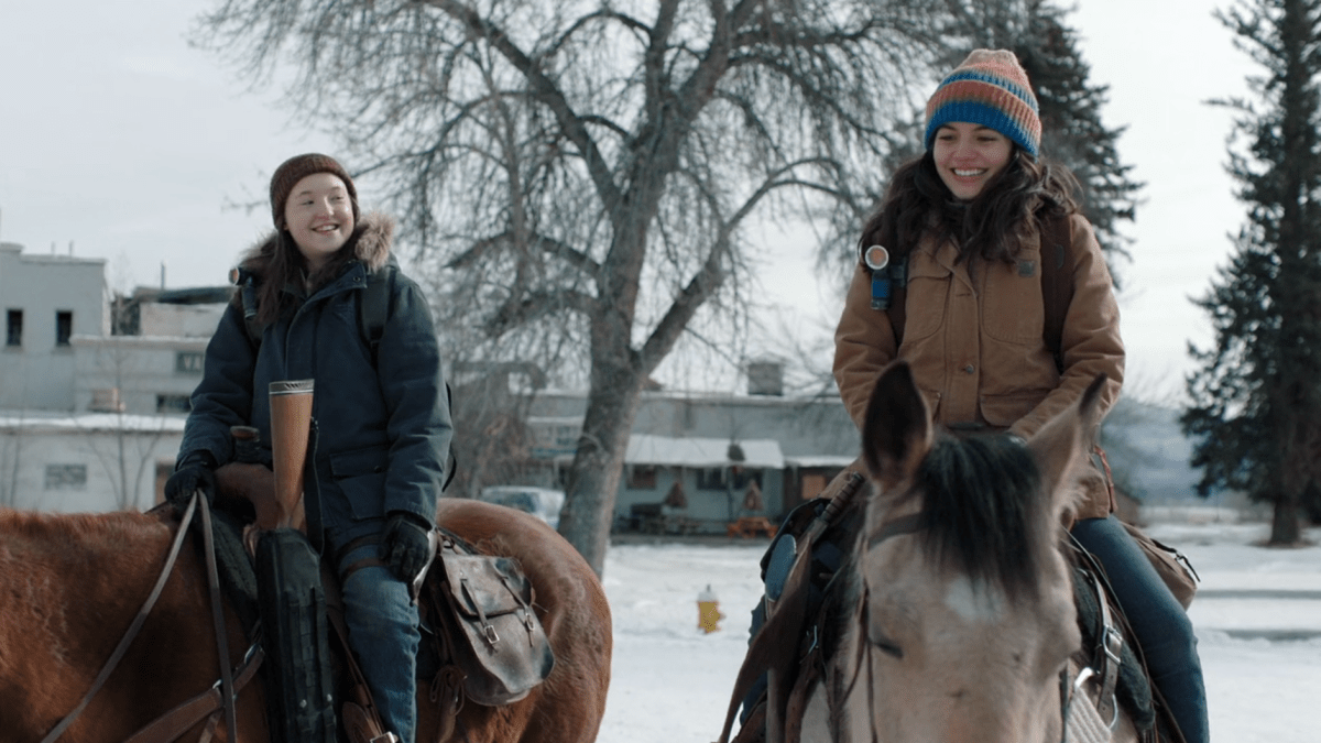 The Last of Us: Ellie and Dina sit on their horses smiling out on patrol
