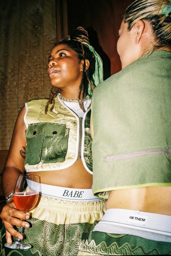 two attendees at the FOR THEM x BABE wine bar event wear BABE underwear, hold wine