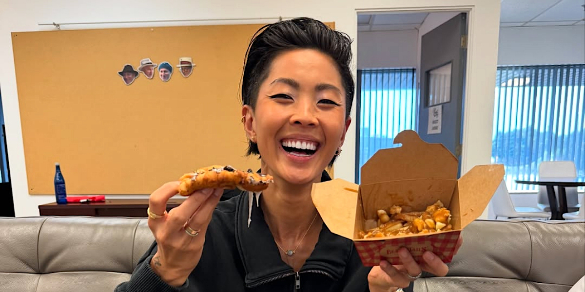 Kristen Kish smiles while eating a beaver tail and poutine