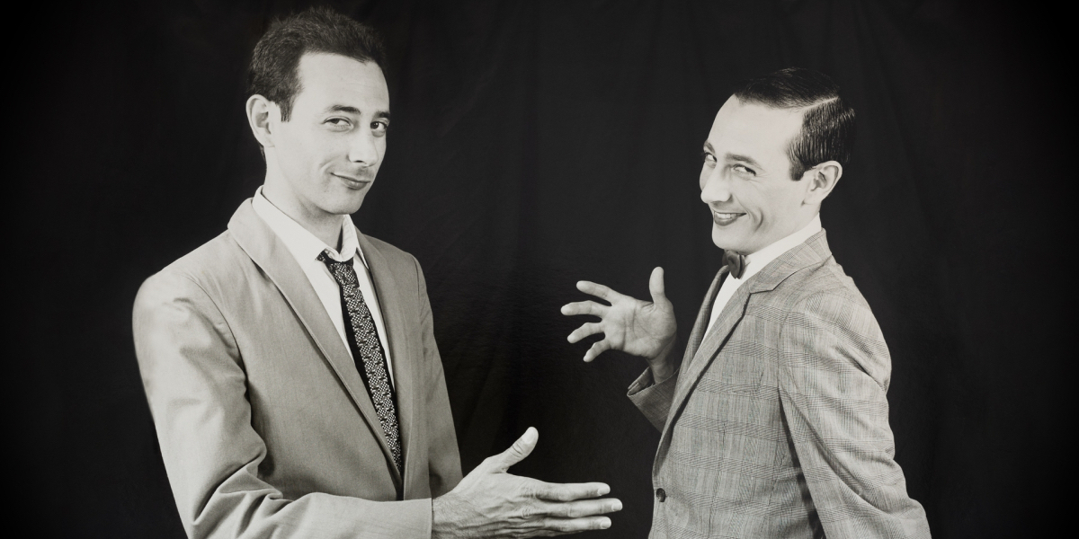 Paul Reubens shakes Pee-wee's hand in trick photograph.