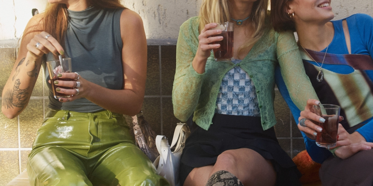 Third wheel: A person with tattoos sits next to a queer couple holding hands.