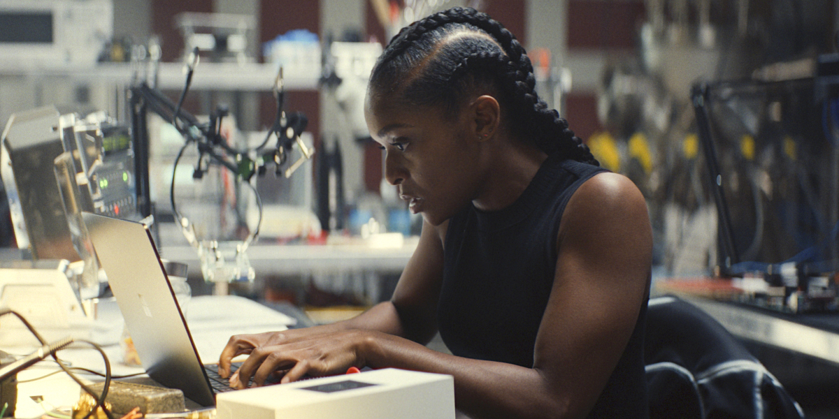 Riri sits at a laptop in Ironheart.