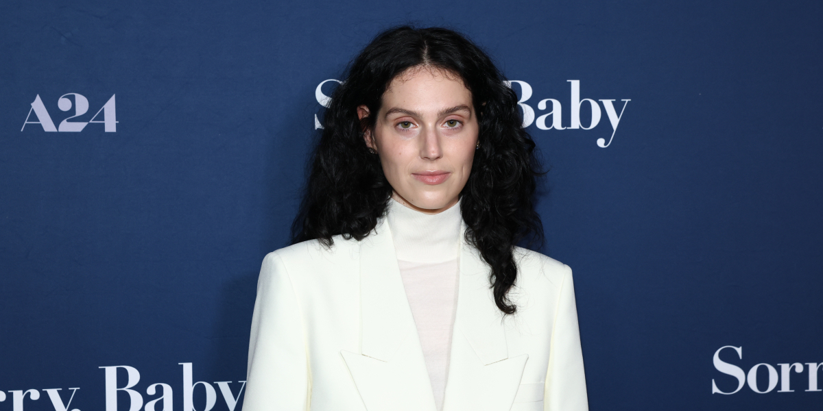 Eva Victor poses at a Sorry, Baby screening dressed in a white turtleneck and white suit jacket.