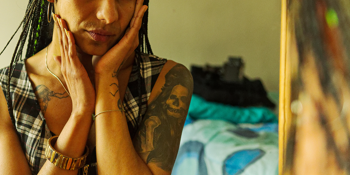 Effects of estrogen: a cropped photo of a trans woman lookin in the mirror with her hands on her face