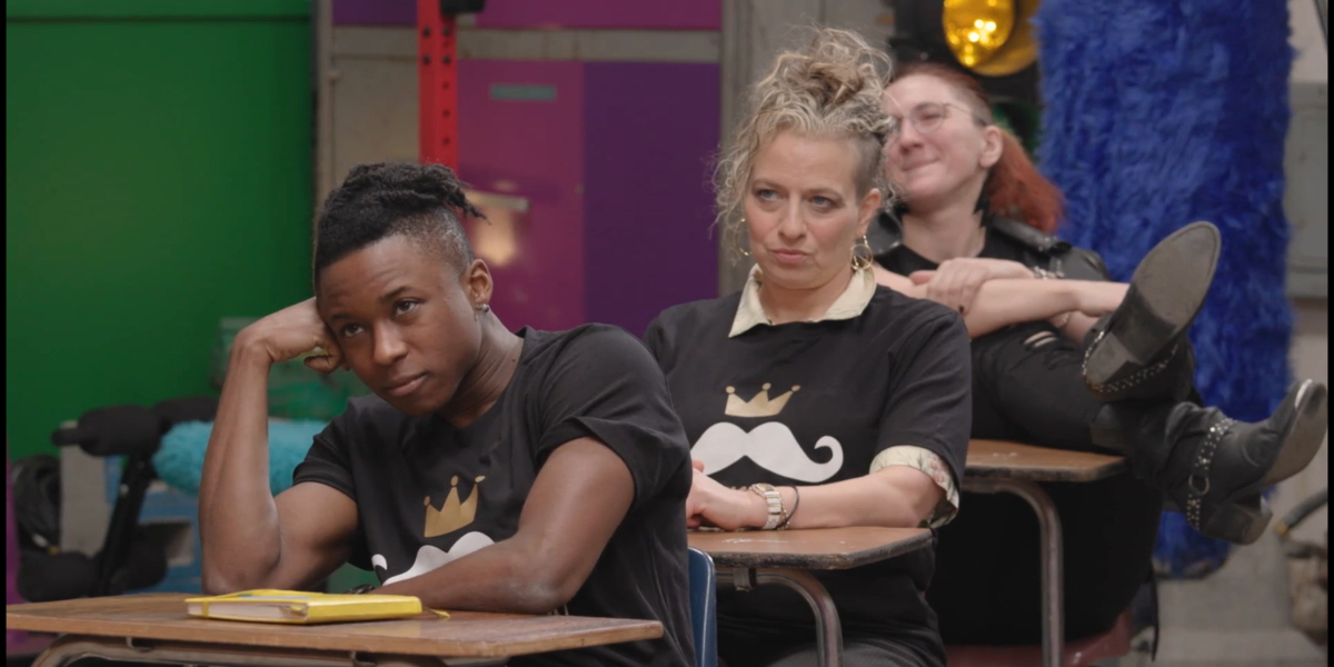 King of Drag 104 recap: Mo, Big D, and Henlo sit at school desks looking like bored students.