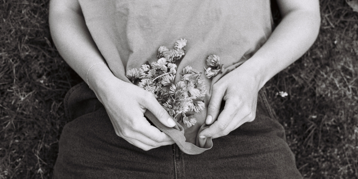 a person holding flowers in their shirt in black and white